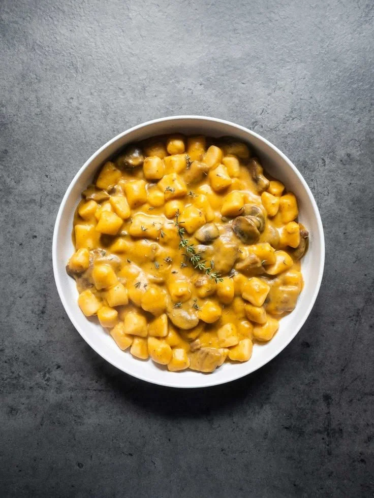 Gnocchi di ceci con crema di zucca e funghi serviti in un piatto elegante.